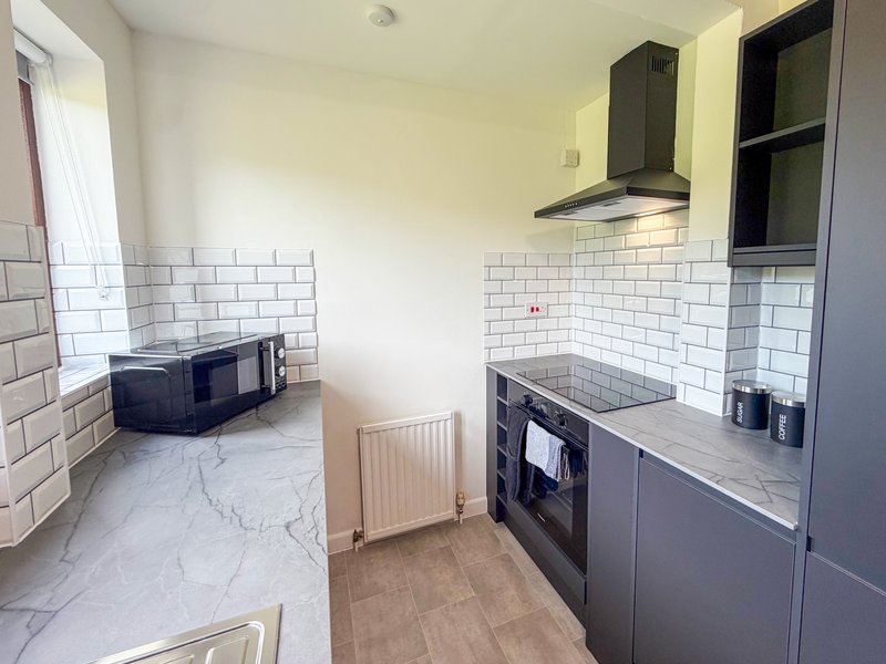 Modern kitchen with white subway tile, grey cabinetry, integrated oven and extractor hood