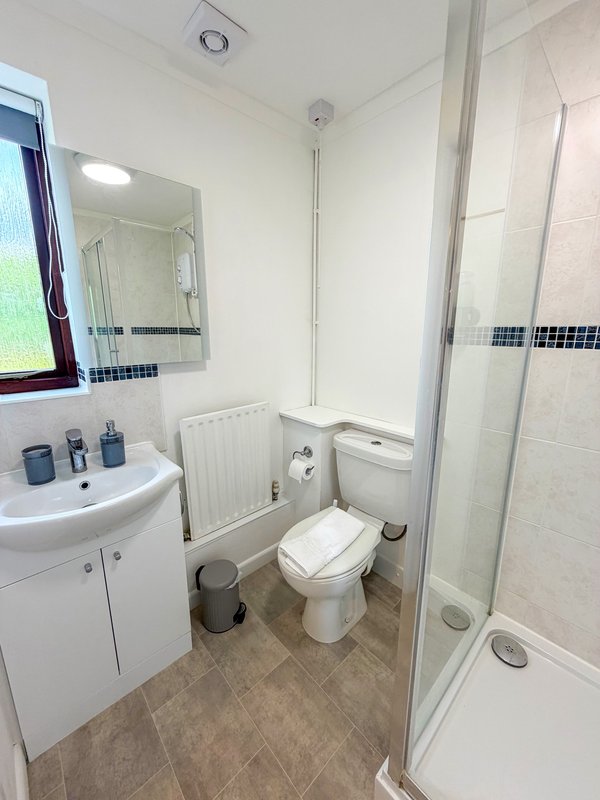 Modern bathroom with white sink, toilet, shower enclosure and tiled flooring