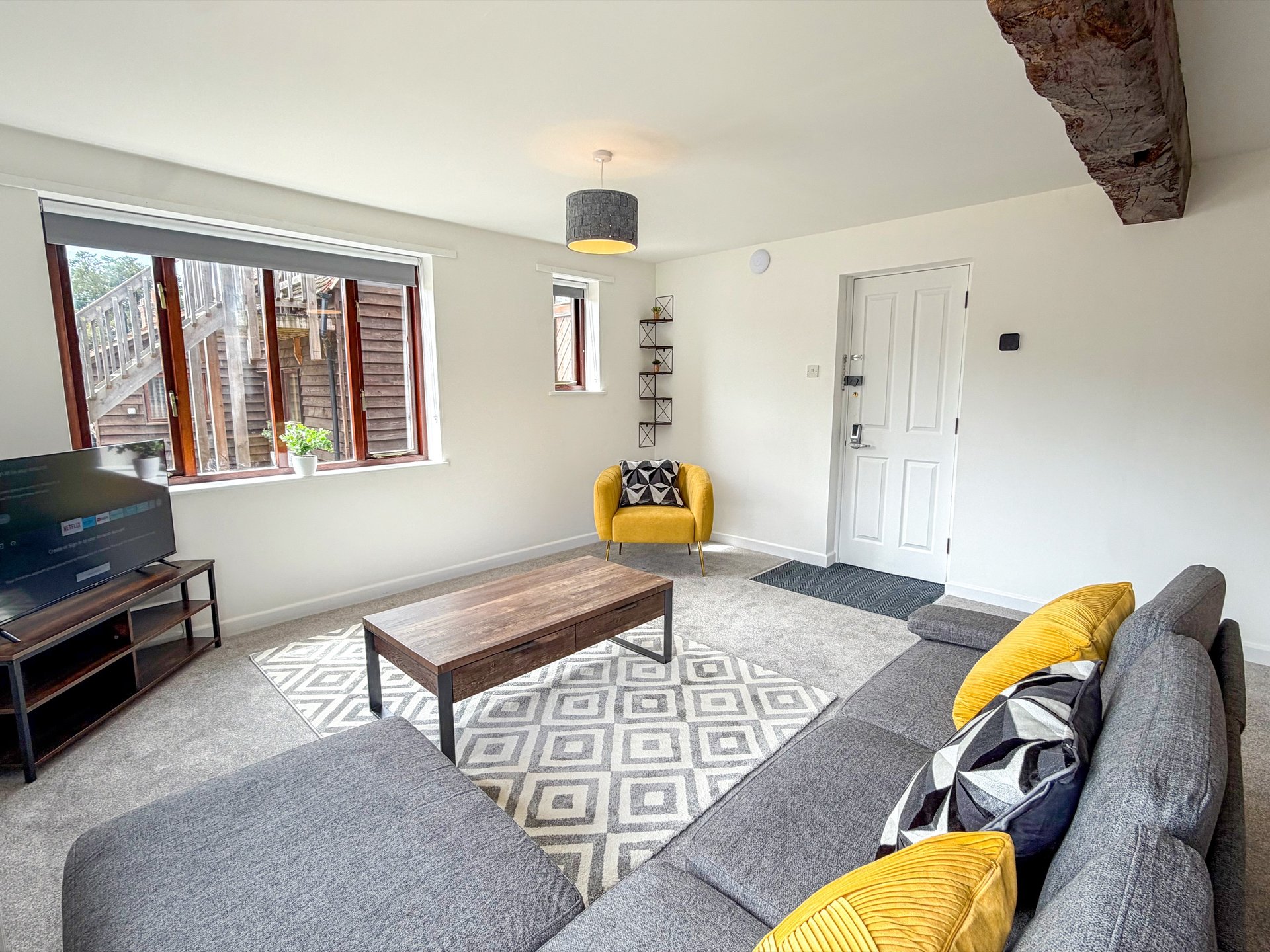 Bright living room with gray sofa, wooden coffee table, yellow accent chair and geometric rug