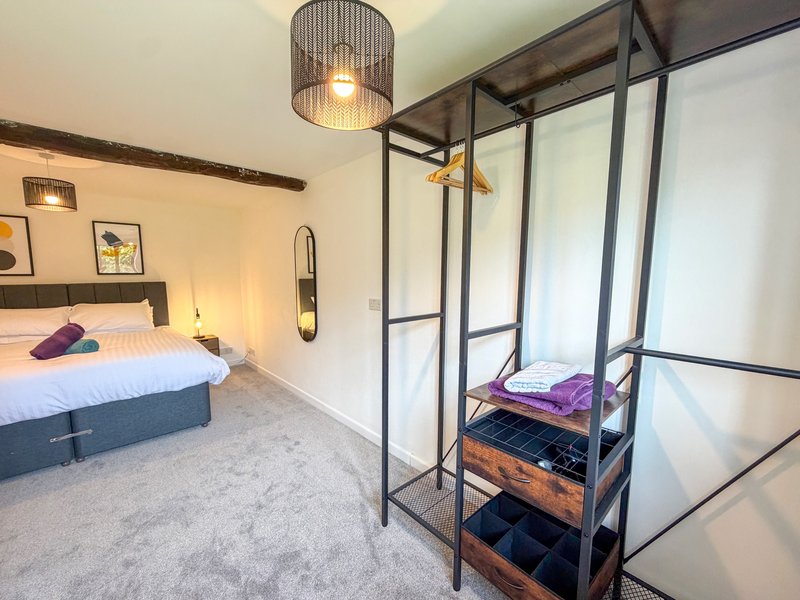 Modern bedroom with double bed, pendant light, wardrobe with glass doors and shelving