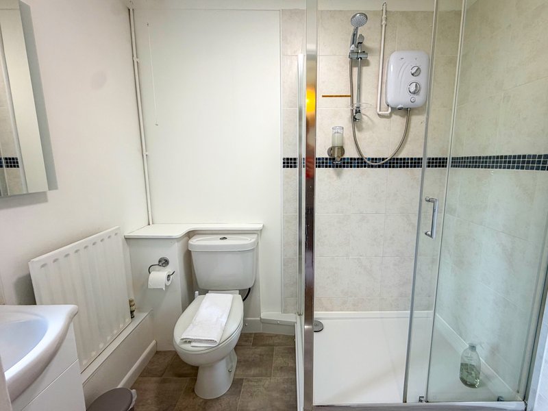 Modern bathroom with toilet, sink, radiator, shower enclosure and decorative tile border