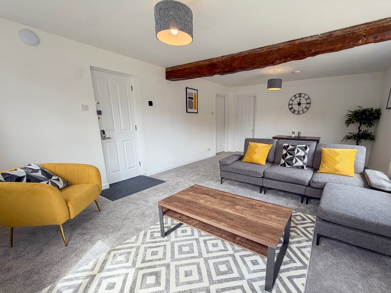 Modern living room with gray sofa, yellow armchair, wooden coffee table and pendant light