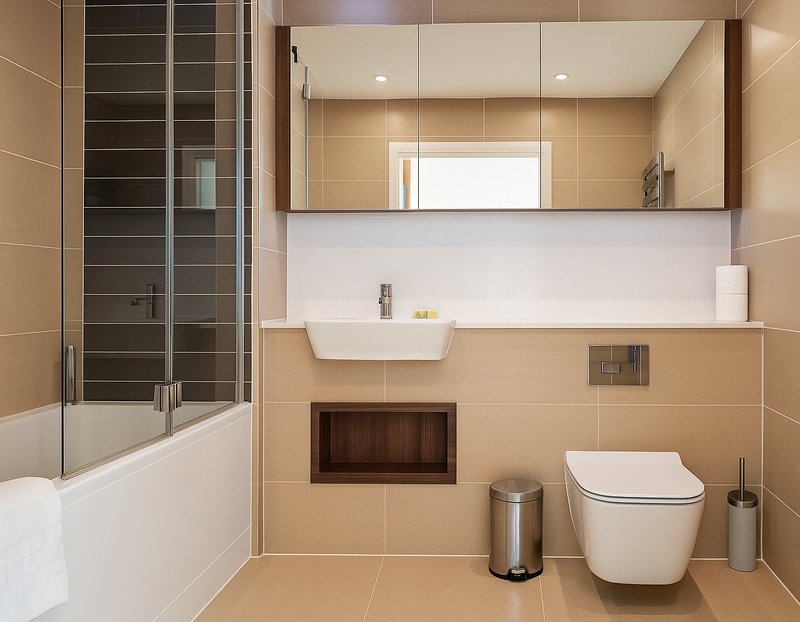 Modern bathroom with large mirror, white sink, toilet, shower enclosure and beige tile walls