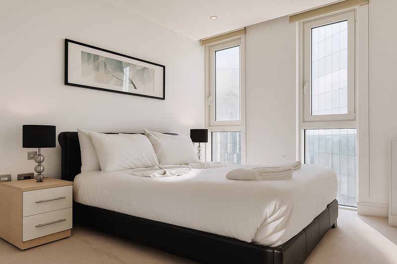 Modern bedroom with double bed, black headboard, wooden nightstands and bright windows