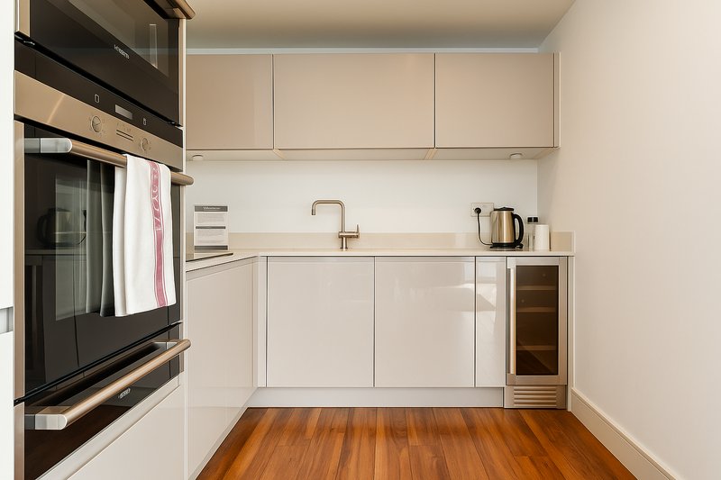 Modern kitchen with cream cabinetry, black oven, wooden flooring and stainless steel fixtures