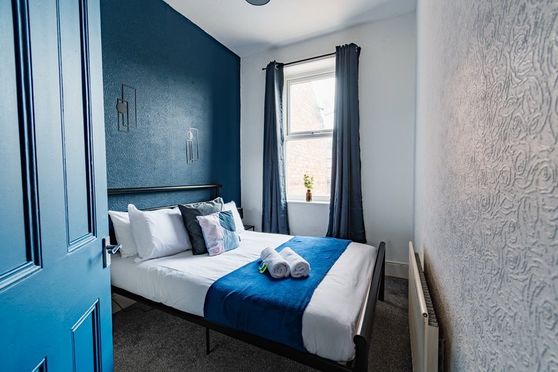 Modern bedroom with double bed, blue accent wall, white pillows and blue bedding