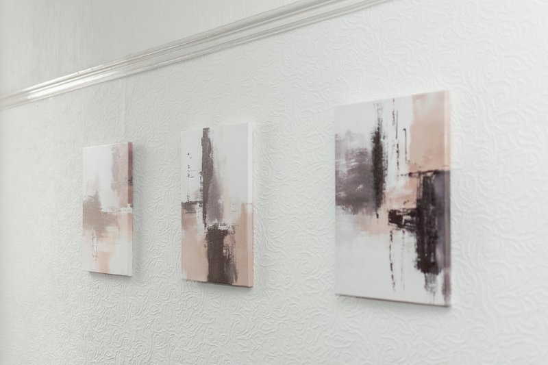 White wall with three abstract art prints in muted brown and beige tones
