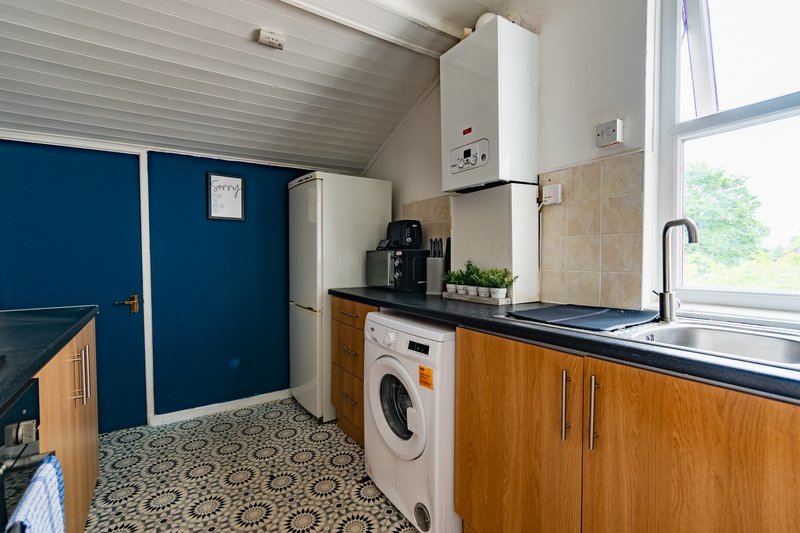 Kitchen with wooden cabinets, washing machine, sink, and blue-painted utility room door