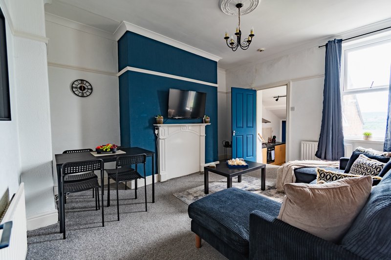 Open-plan living room with blue accent wall, dining table, fireplace, and comfortable seating
