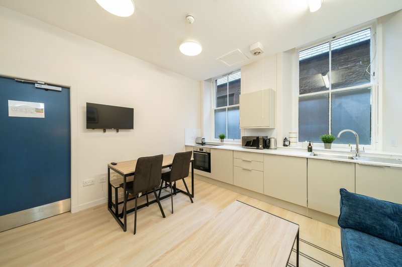 Modern open-plan kitchen and dining area with wooden flooring, cream cabinetry, and blue accents