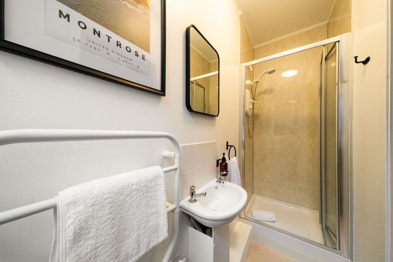 Modern bathroom with shower enclosure, wall-mounted sink, and heated towel rail