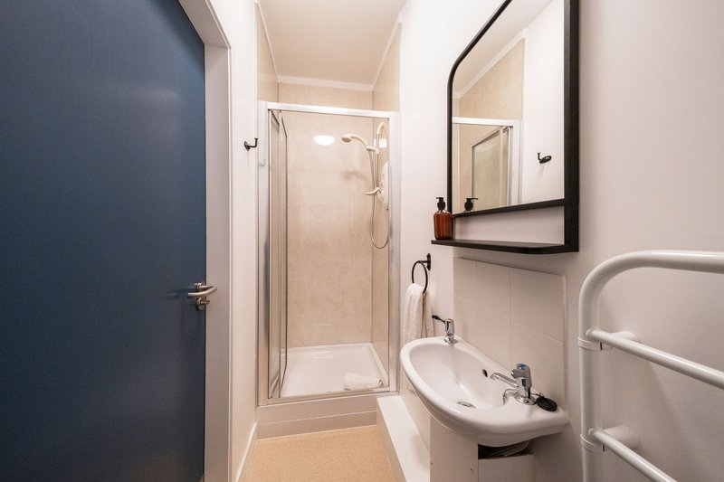 Modern bathroom with shower cubicle, white sink, framed mirror and towel rail