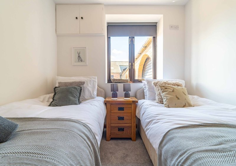 Twin bedroom with two single beds, wooden bedside table, and patio doors with sea view