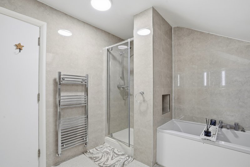 Modern bathroom with shower enclosure, heated towel rail, white bathtub and recessed lighting