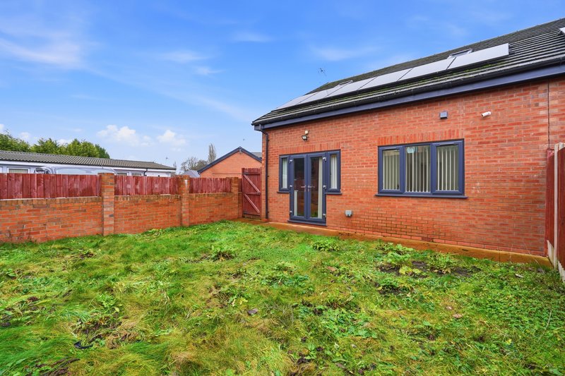 Modern brick bungalow exterior with patio doors, garden, and red fence