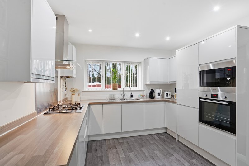 Modern white kitchen with wooden countertops, stainless steel appliances, and natural light
