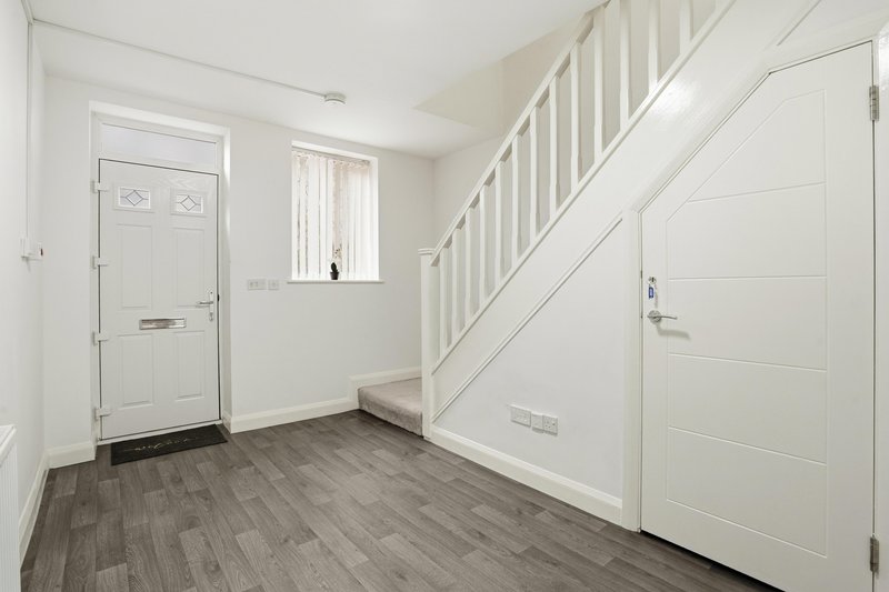 Bright hallway with staircase, white doors, wooden flooring and window light