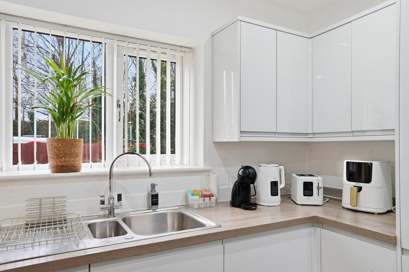 Modern kitchen with white cabinetry, double sink, countertop appliances and garden view