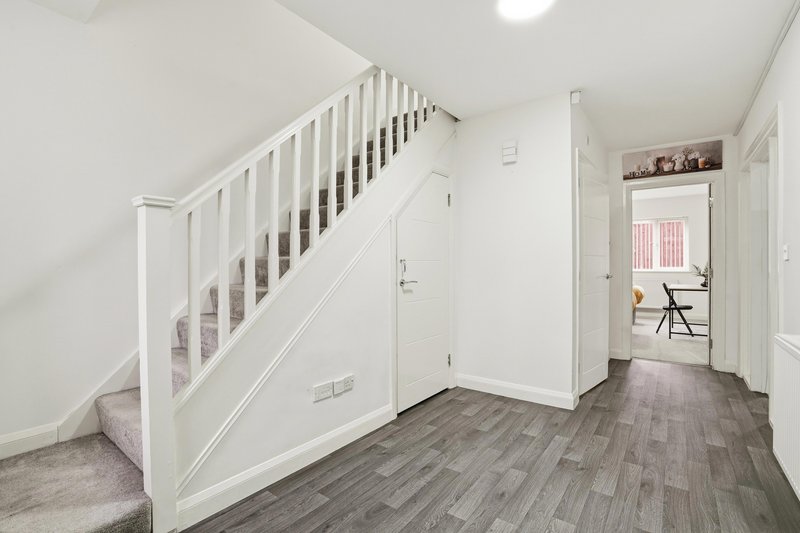 Bright entryway with white staircase, gray wood-effect flooring and open doorway