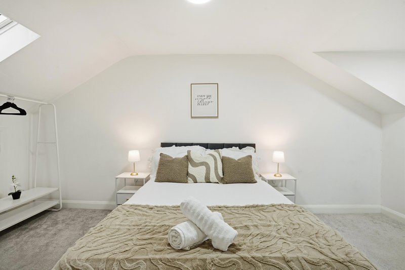 Bright attic bedroom with double bed, neutral bedding, bedside lamps and skylight