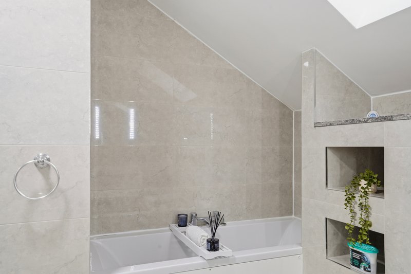 Modern bathroom with double sink, glass shower enclosure, beige tile walls