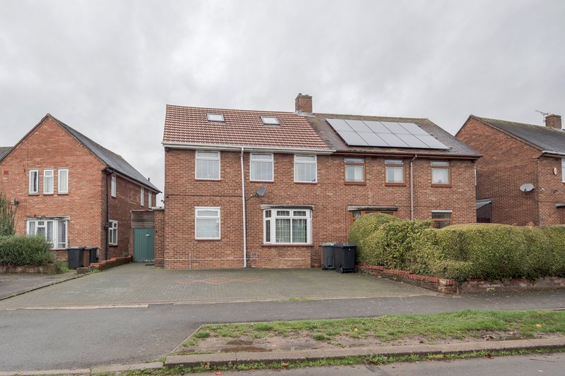 Red brick semi-detached house with driveway, solar panels, and front garden
