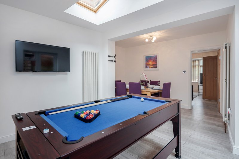 Games room with pool table, wall-mounted TV, purple seating and skylight