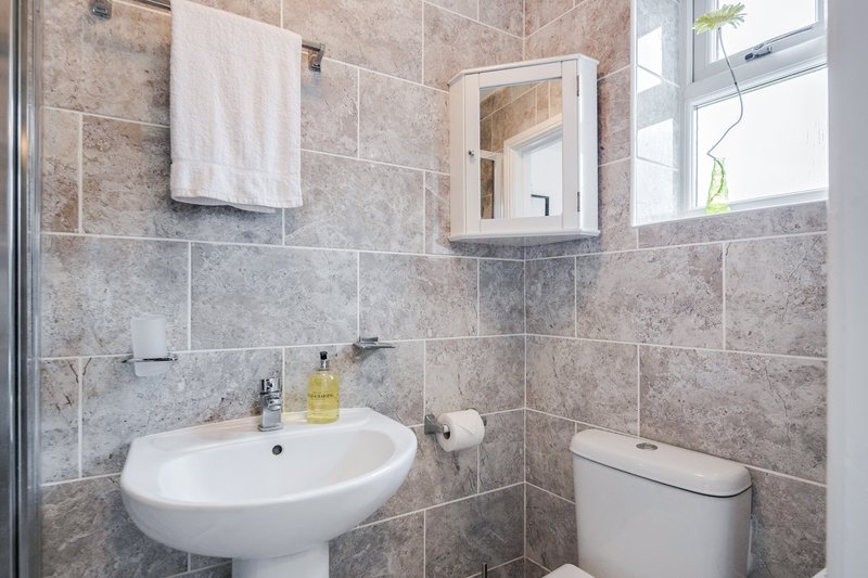 Bathroom with pedestal sink, mirror cabinet, toilet, and tiled walls