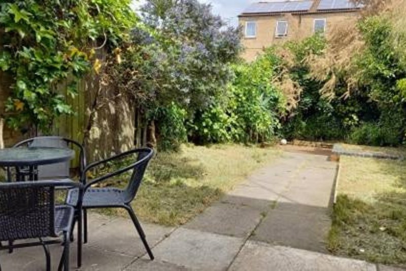 Patio garden with seating area, lawn, ivy-covered walls and brick house