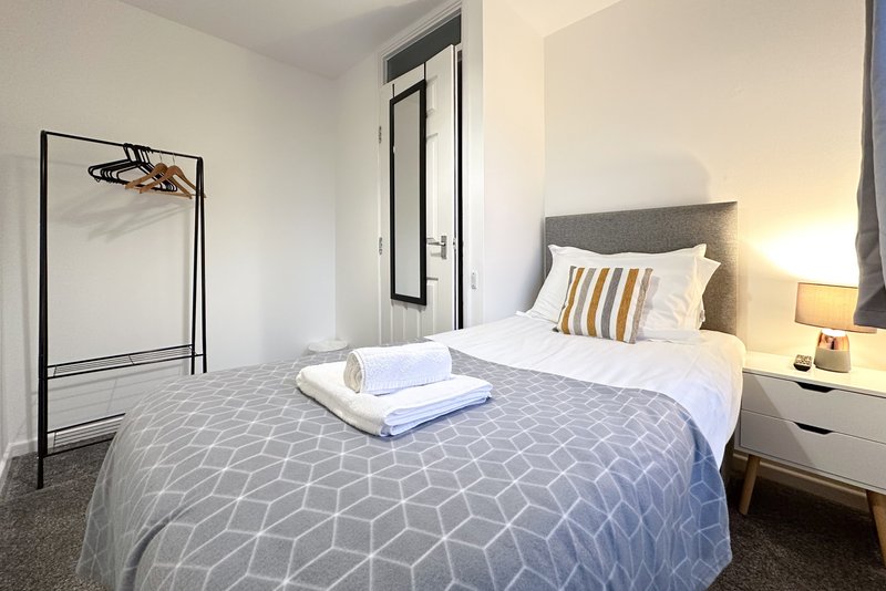 Modern bedroom with double bed, bedside lamp, white pillows and geometric patterned bedding