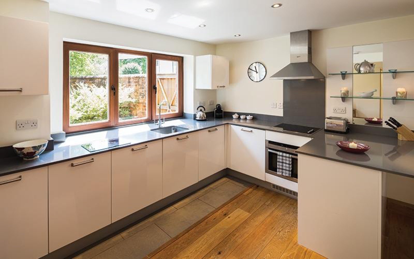 Modern kitchen with cream cabinets, dark worktops, stainless steel appliances and garden views