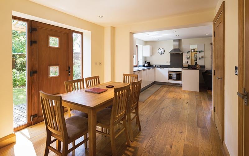 Open-plan dining and kitchen area with wooden table, chairs, and modern appliances