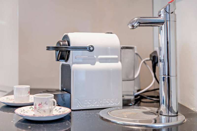 Kitchen counter with white coffee machine, mugs, and chrome tap