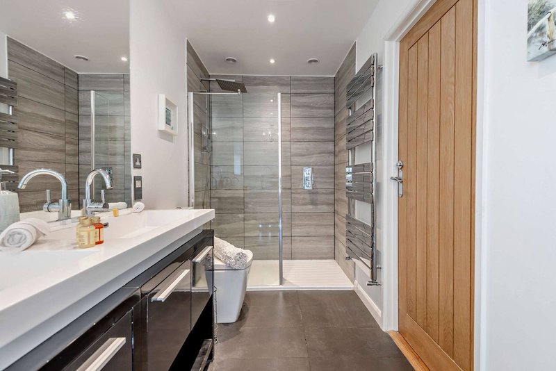 Modern bathroom with double sink, walk-in shower, and heated towel rail