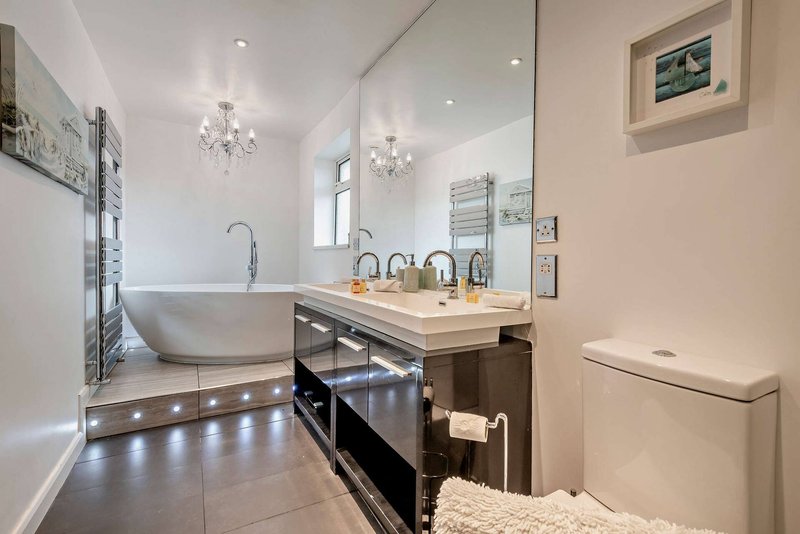 Modern bathroom with freestanding bathtub, double vanity sink, large mirror and heated towel rail