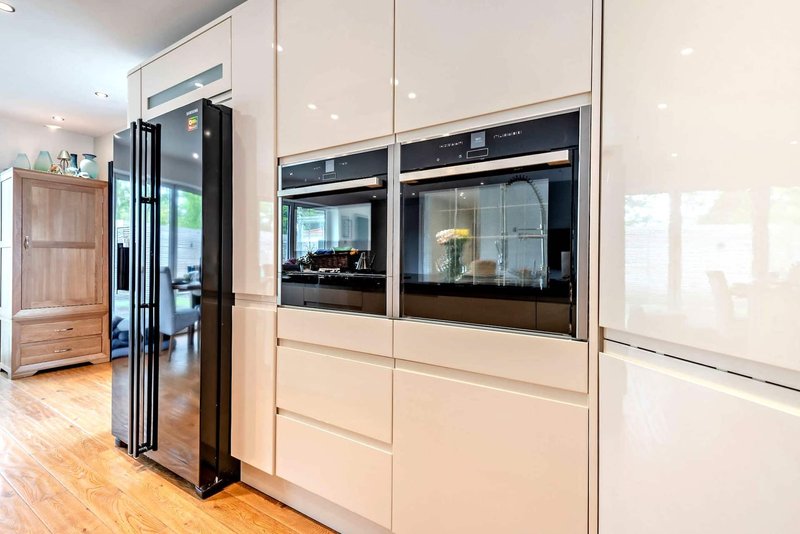 Modern kitchen with cream cabinets, built-in black appliances, and wooden flooring
