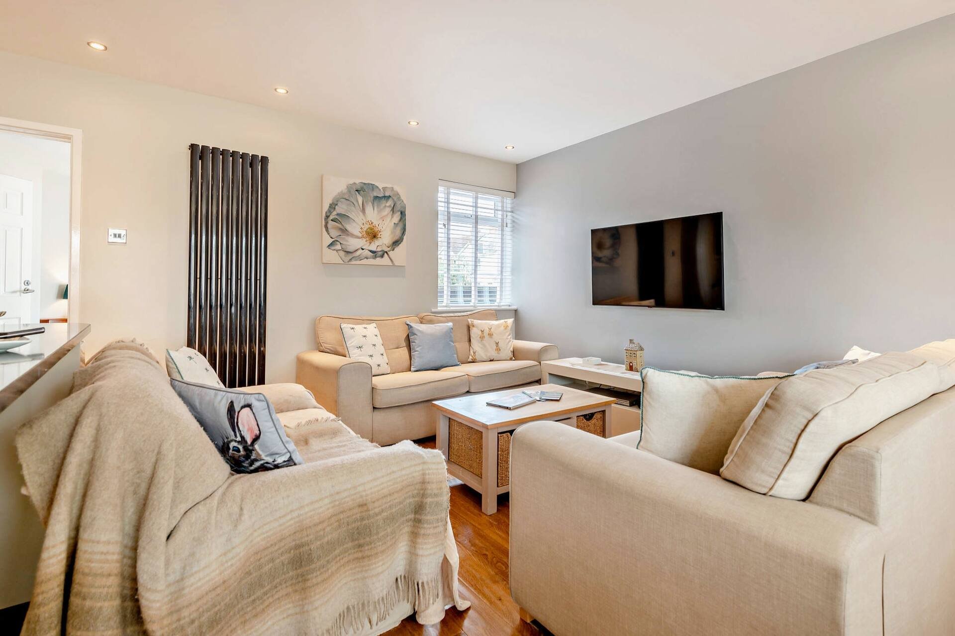 Modern living room with beige sofas, wooden coffee table, wall-mounted TV and warm lighting