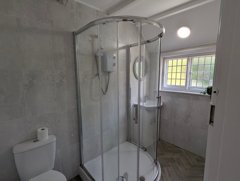 Practical, fully tiled bathroom with a generous enclosed shower, WC and wash basin. A good-sized shower provides a convenient setup for contractors to freshen up and unwind after a day on site.