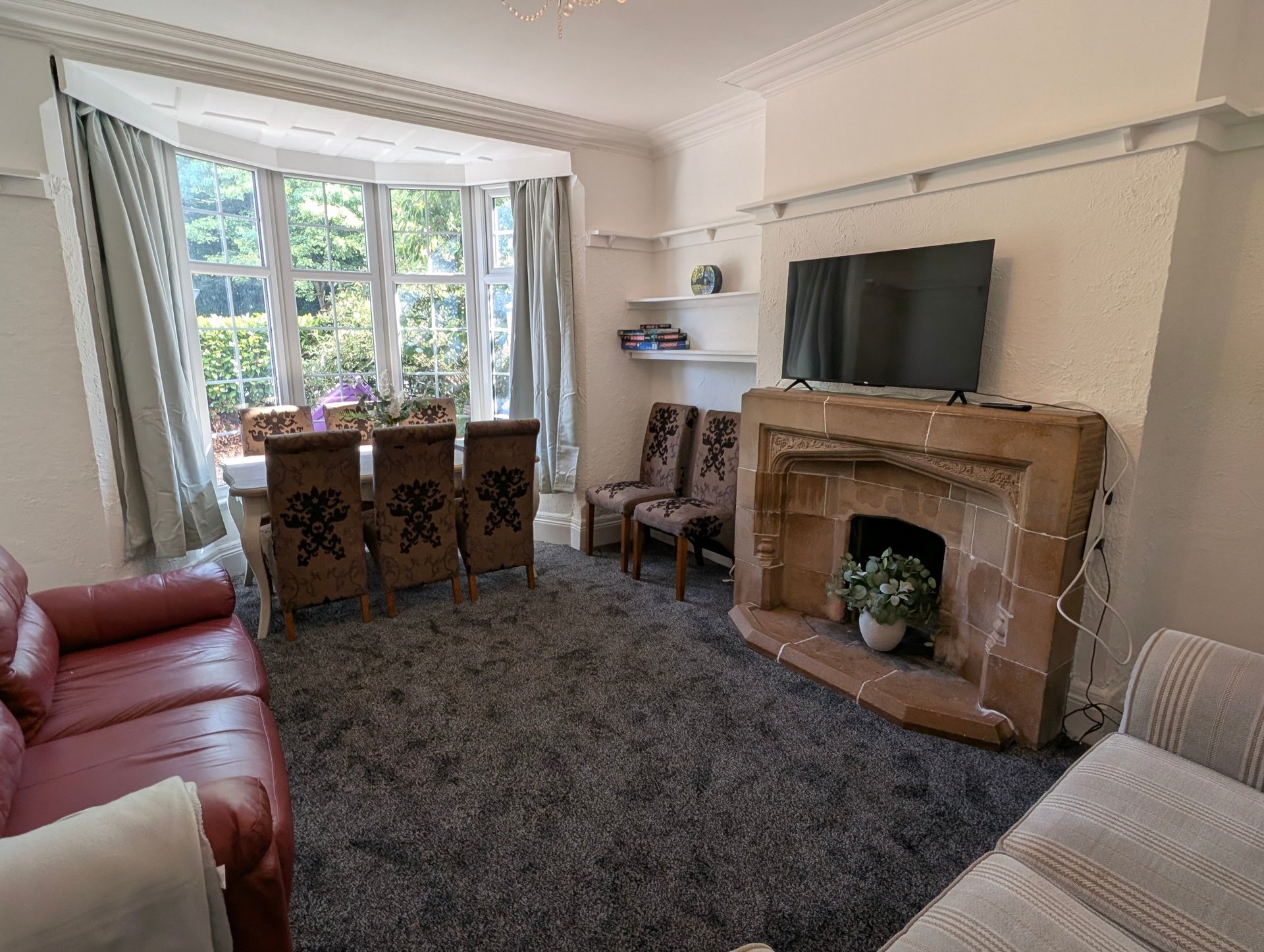 Spacious, comfortable living room providing a welcoming space for groups to relax after a busy day, with plenty of seating, a dining area, TV and a traditional feature fireplace.