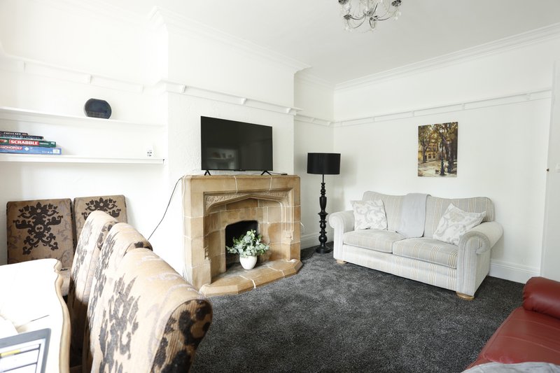Spacious communal lounge with comfortable seating, a TV and traditional fireplace, giving groups plenty of room to relax after work. The open layout also connects naturally with the dining area.