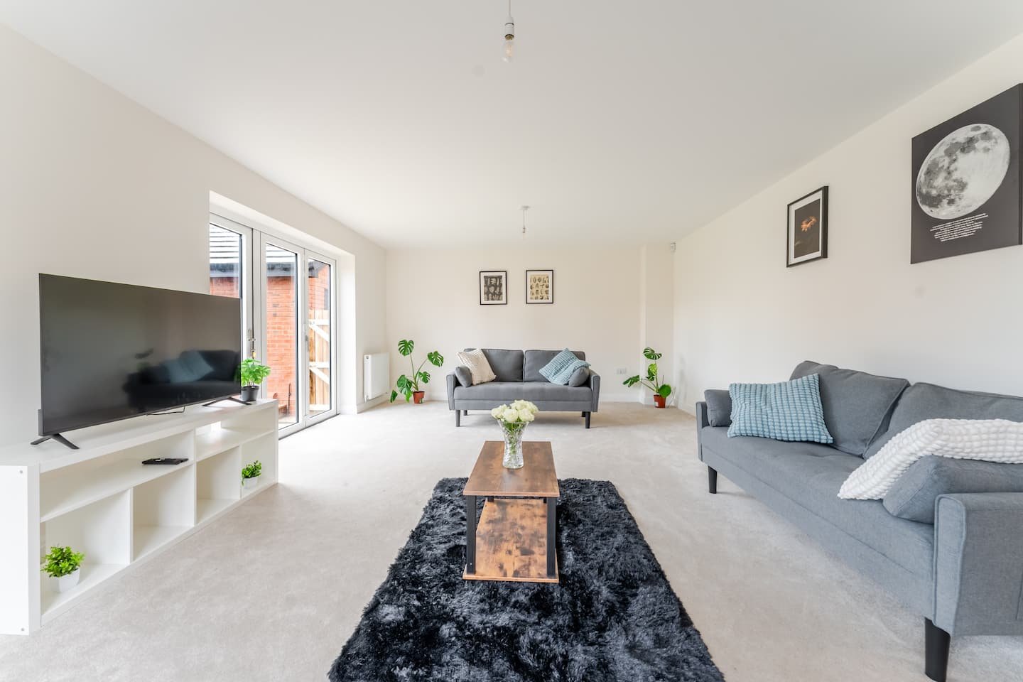 Spacious living room with gray sofas, TV, wooden coffee table, and large windows