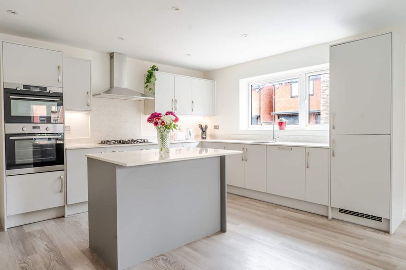 Modern kitchen with white cabinetry, central island, stainless steel appliances and bright windows