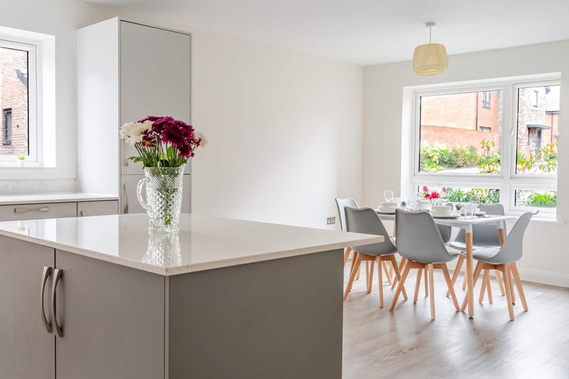 Modern open-plan kitchen and dining area with island, dining table, and garden view