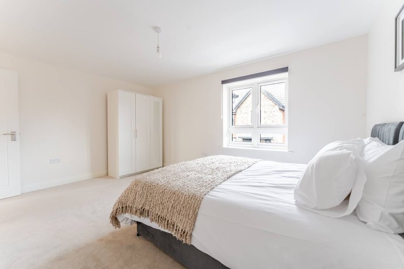Bright modern bedroom with double bed, wardrobe, and large window overlooking street