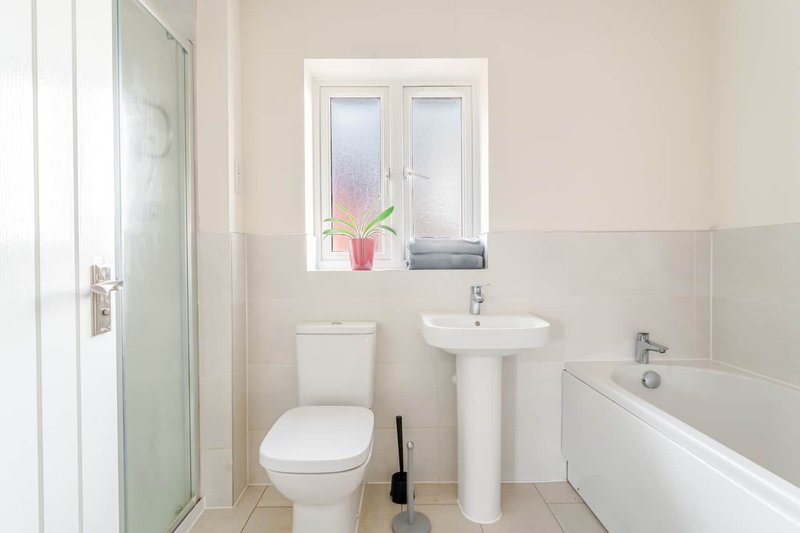 Clean modern bathroom with toilet, pedestal sink, bathtub and shower enclosure