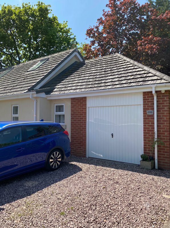 Modern brick house with driveway, white garage door, and parked blue car