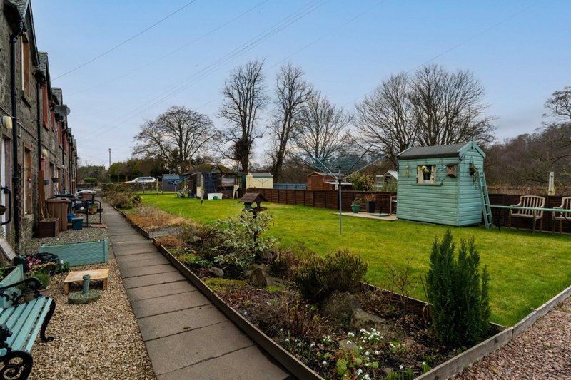 Garden view with lawn, planted borders, shed, and stone patio pathway