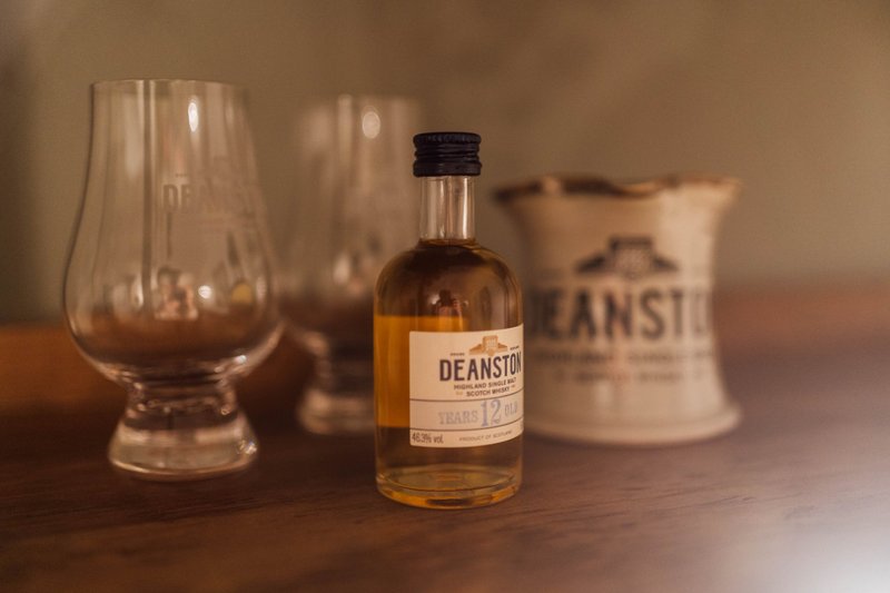 Whisky bottle with glass and branded vessel on wooden surface