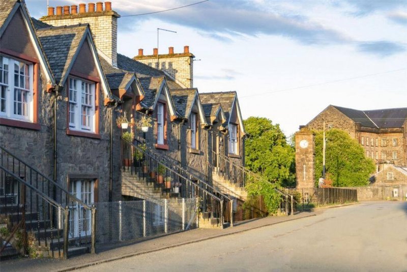 Stone terraced houses with yellow chimneys lining a quiet village street