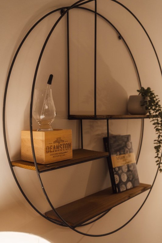 Circular wall-mounted shelving unit with decorative items and trailing plant